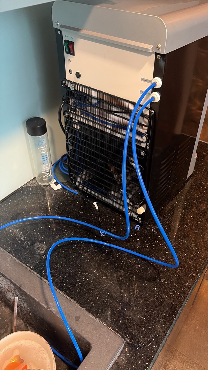 Back of the Minairal Tap Water Pure Countertop with blue hoses connected to the water inlet and waste-water ports