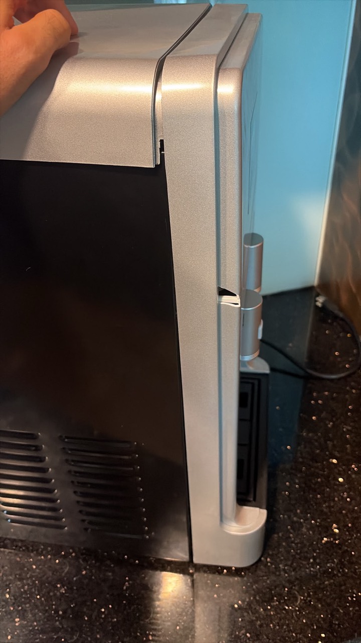 Side of the unit with the top cover out of line and a cracked panel next to the taps