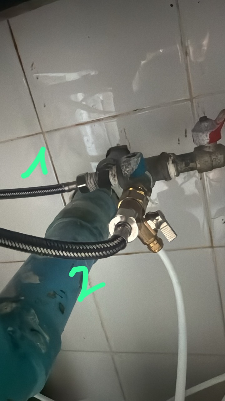Wall plumbing with a brass tee, valve and hoses marked 1 and 2